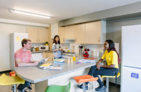 A group sit together in their accommodation halls kitchen
