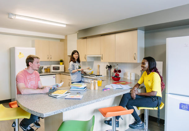 A group sit together in their accommodation halls kitchen