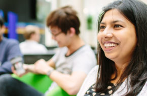 A woman smiles to somebody off-camera during a drop-in session for Postgraduates