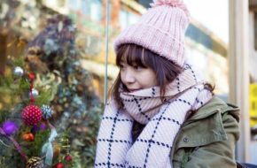 A woman looks in a shop window filled with Christmas decorations