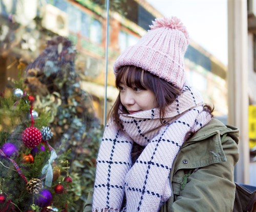 A woman looks in a shop window filled with Christmas decorations