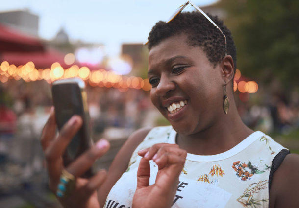 A woman smiling whilst using her smartphone
