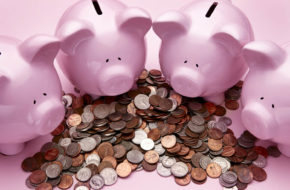 Four piggy banks surrounding a pile of small UK changes