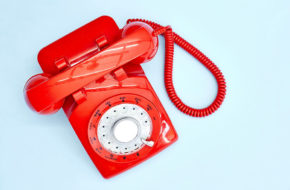 A shiny red telephone on a blue background
