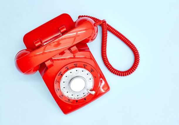 A shiny red telephone on a blue background