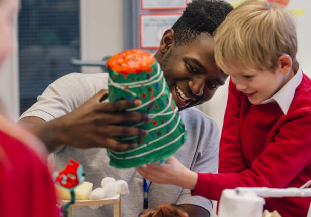 A man helps a child with a model in a classroom