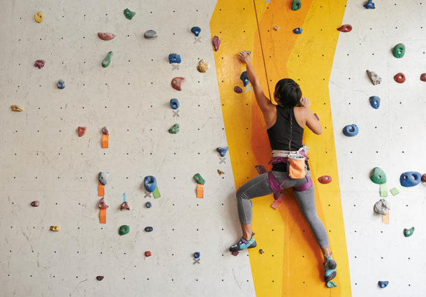 A woman using an indoor rock climbing wall