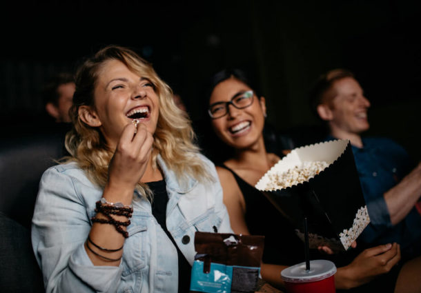 Two women with popcorn laughing in the cinema