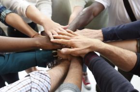 Several hands joined together in the middle of a circle