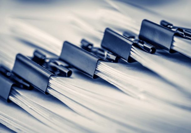 A close up of piles of documents joined together with bulldog clips