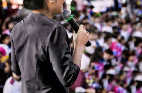 A woman with a microphone addresses an audience