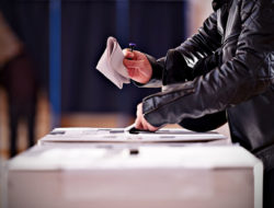 Close up of somebody casting a vote in a ballot box