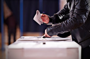 Close up of somebody casting a vote in a ballot box
