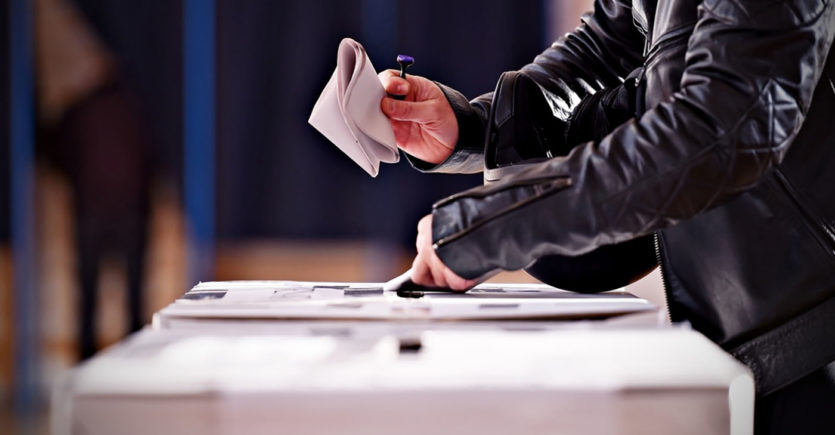 Close up of somebody casting a vote in a ballot box