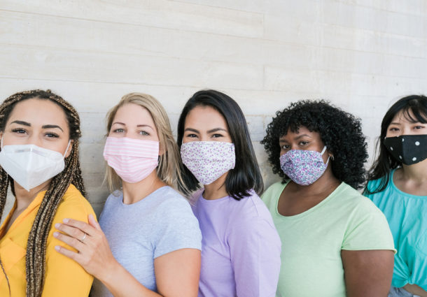 A group of women standing together with masks on